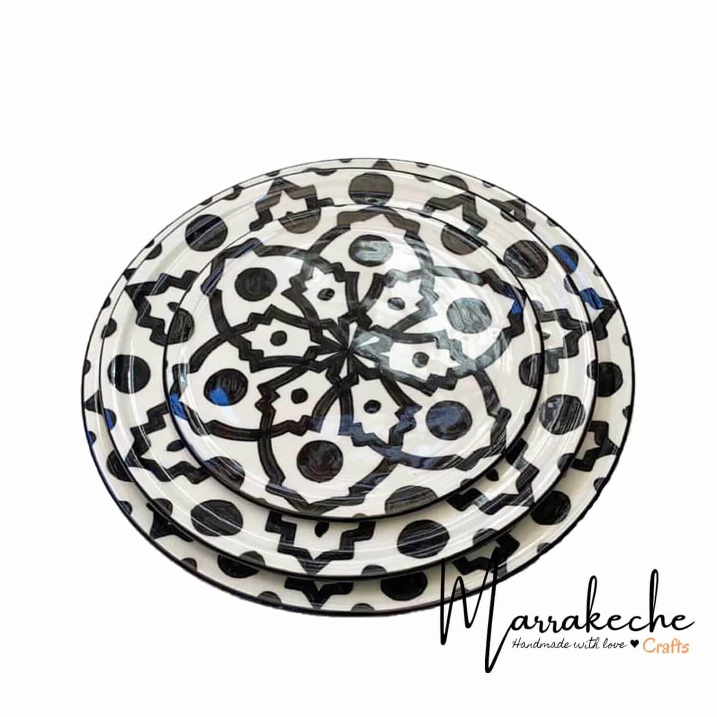 Stacked hand-painted ceramic plates featuring black geometric Safi patterns on cream clay