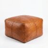 Braided leather square ottoman in cognac with herringbone weave pattern on white background