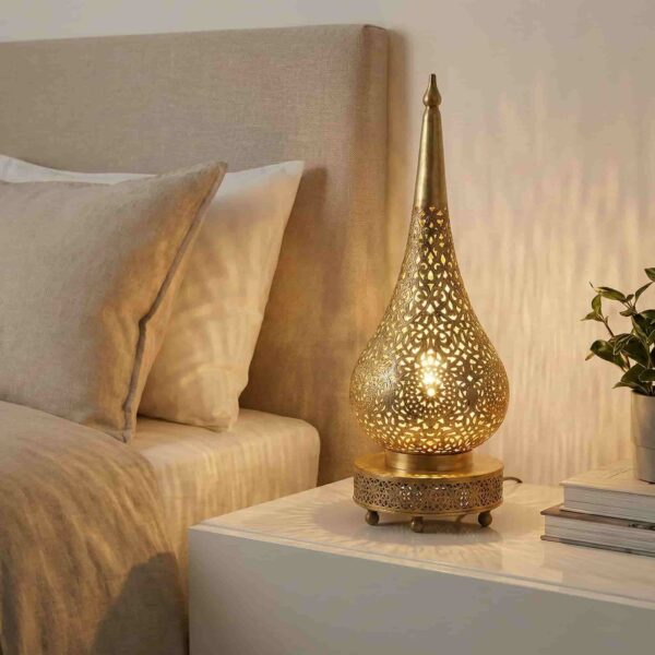 Teardrop brass accent lamp glowing warmly on modern nightstand with stacked books and small plant in neutral bedroom Teardrop brass accent lamp glowing warmly on modern nightstand with stacked books and small plant in neutral bedroom