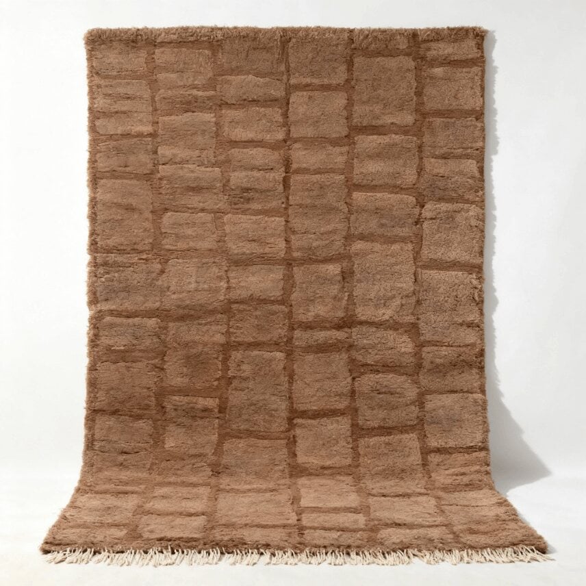 Handwoven Moroccan wool shag rug with geometric grid pattern in natural brown tones on white studio background