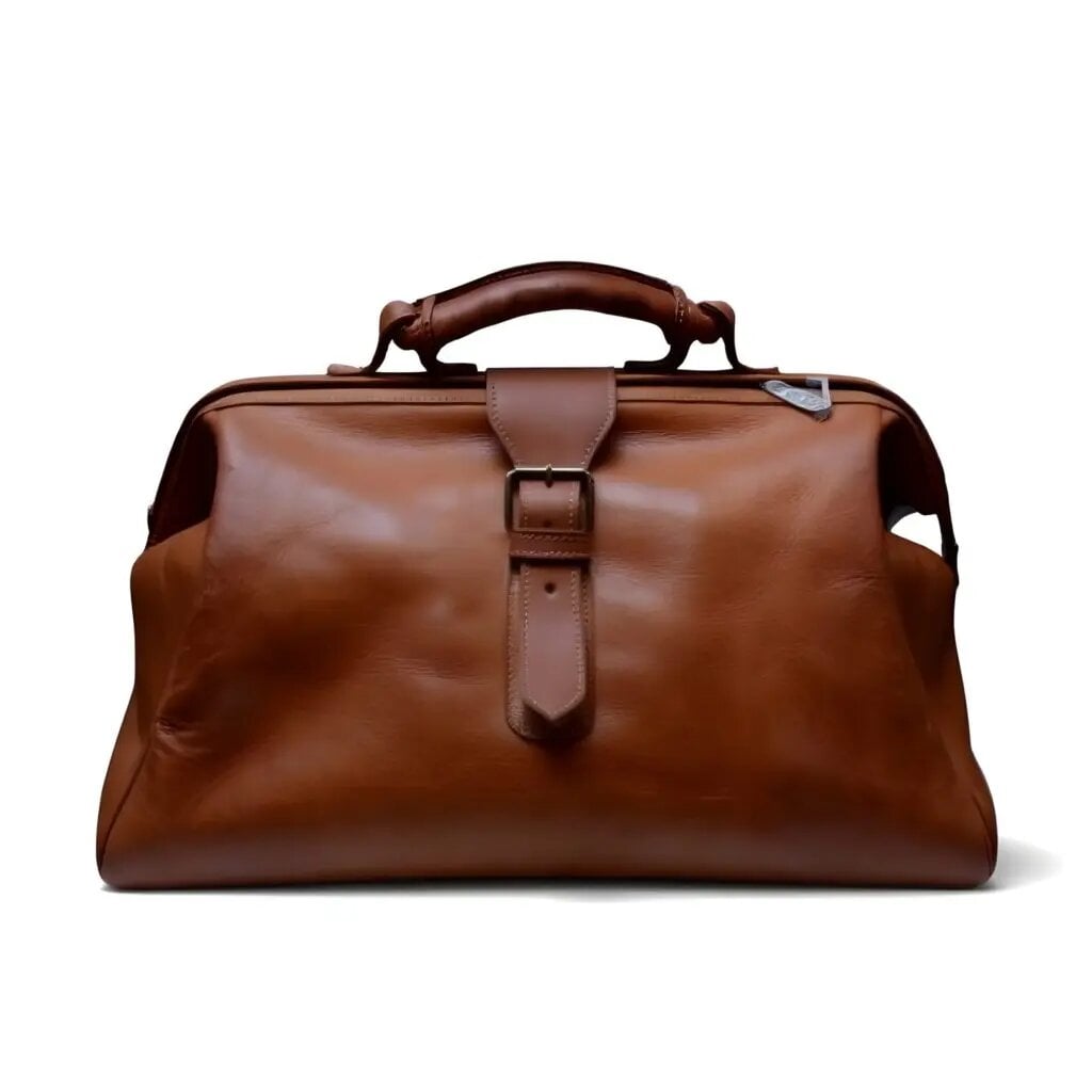 Handcrafted brown leather duffle bag with central buckle strap and brass hardware on white studio background