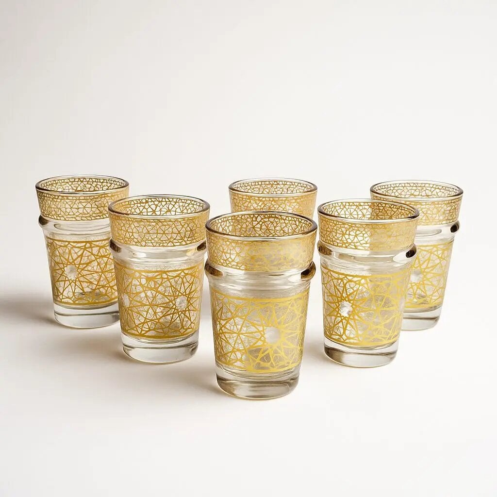 Set of six gold geometric tea glasses with Rub el Hizb star pattern on white backdrop Set of six gold geometric tea glasses with Rub el Hizb star pattern on white backdrop