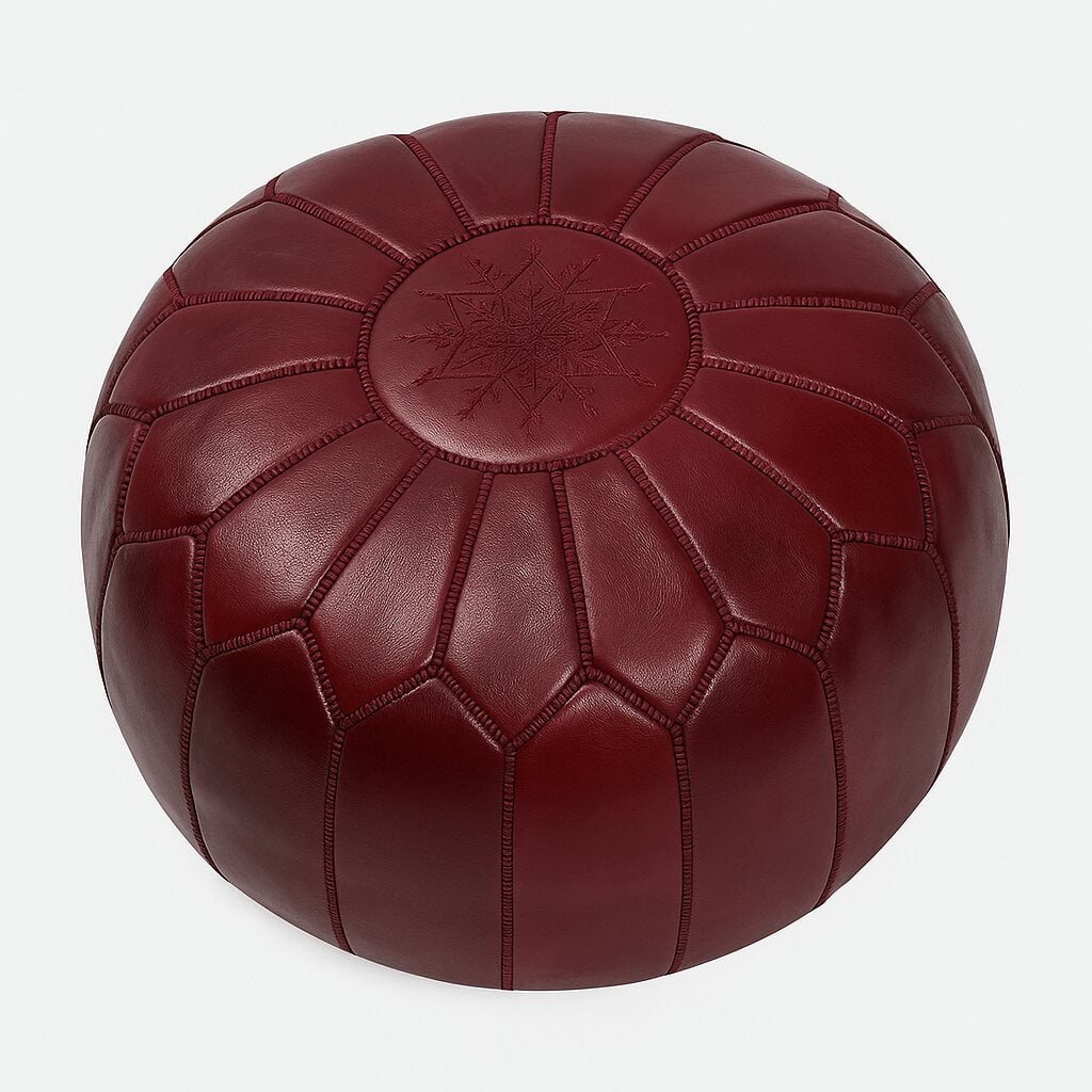 Deep red leather round pouf with embroidered geometric star medallion and whipstitch seams on plain background