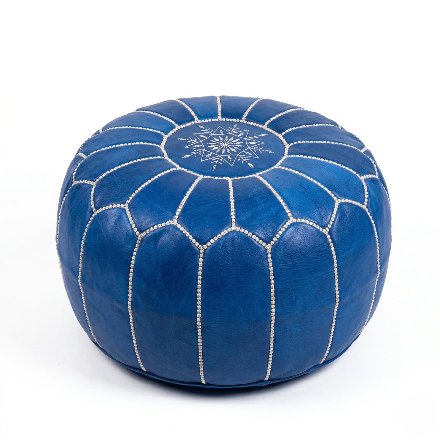 Round denim blue leather floor ottoman with white hand-embroidered geometric pattern on white studio background