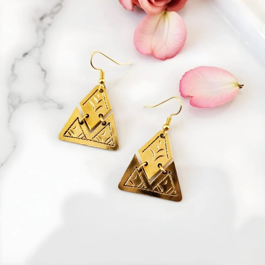 Handcrafted geometric brass earrings with Moroccan triangle design and gold finish on marble surface
