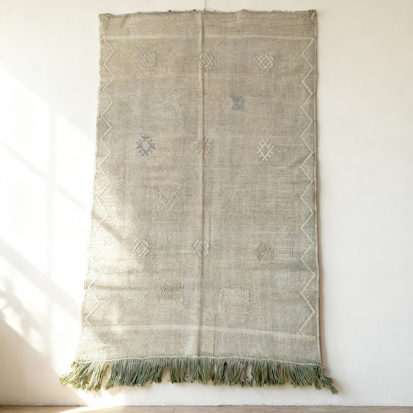 Handwoven green cactus silk rug with geometric Berber motifs and fringed edges laid flat Handwoven green cactus silk rug with geometric Berber motifs and fringed edges laid flat
