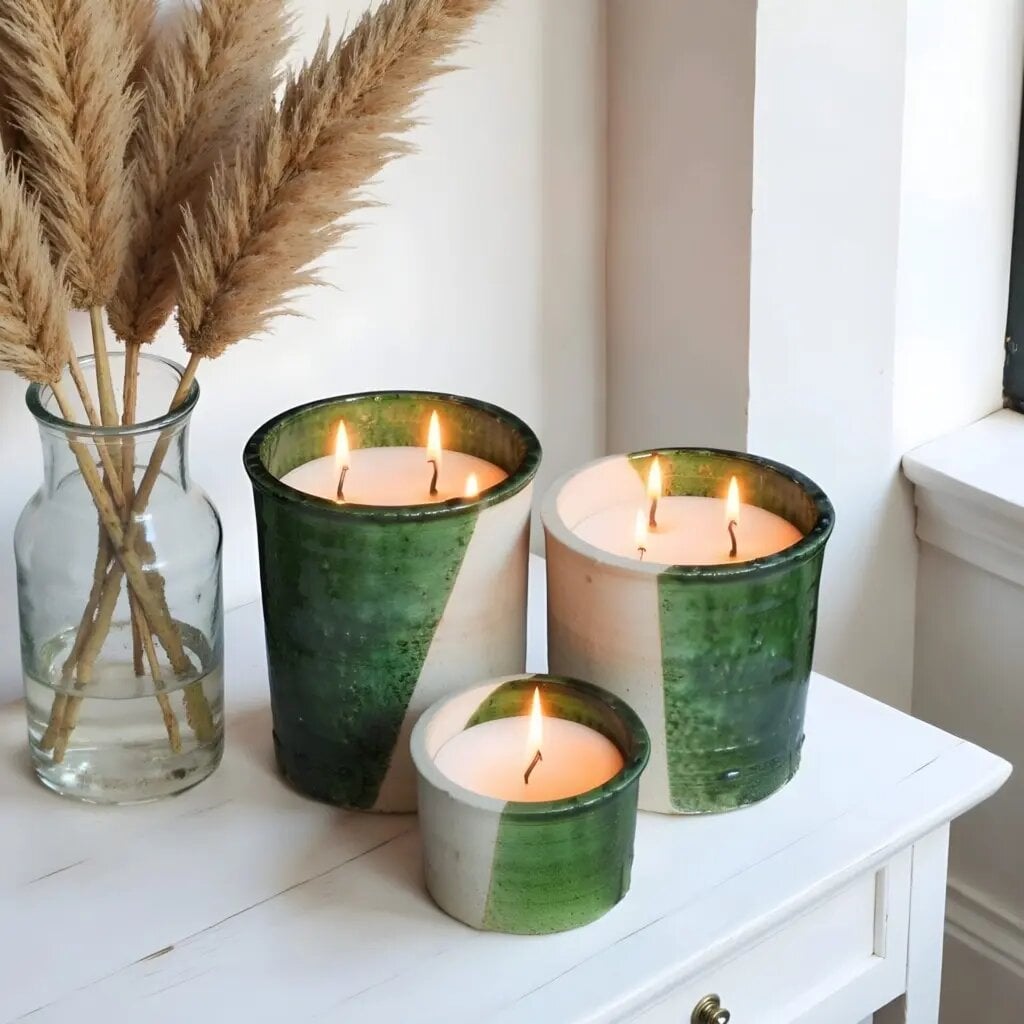 Handmade ceramic candle trio with green Tamegroute glaze displayed with dried pampas grass on white nightstand Handmade ceramic candle trio with green Tamegroute glaze displayed with dried pampas grass on white nightstand