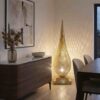 Teardrop brass standing lamp casting intricate shadow patterns in contemporary dining room corner with walnut sideboard and abstract art