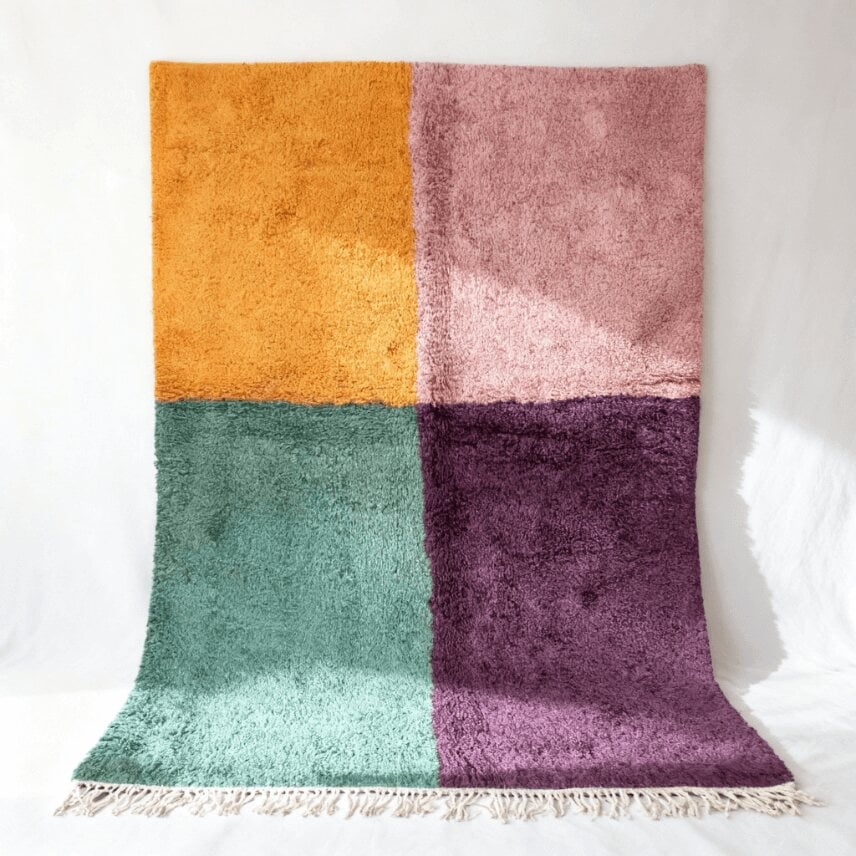 Handwoven color block Moroccan wool rug with purple, green, pink, and yellow quadrants on white background
