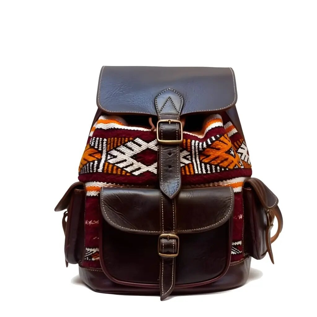 Dark brown leather kilim backpack with handwoven geometric diamond patterns, brass buckle flap closure, and exterior pockets on white background