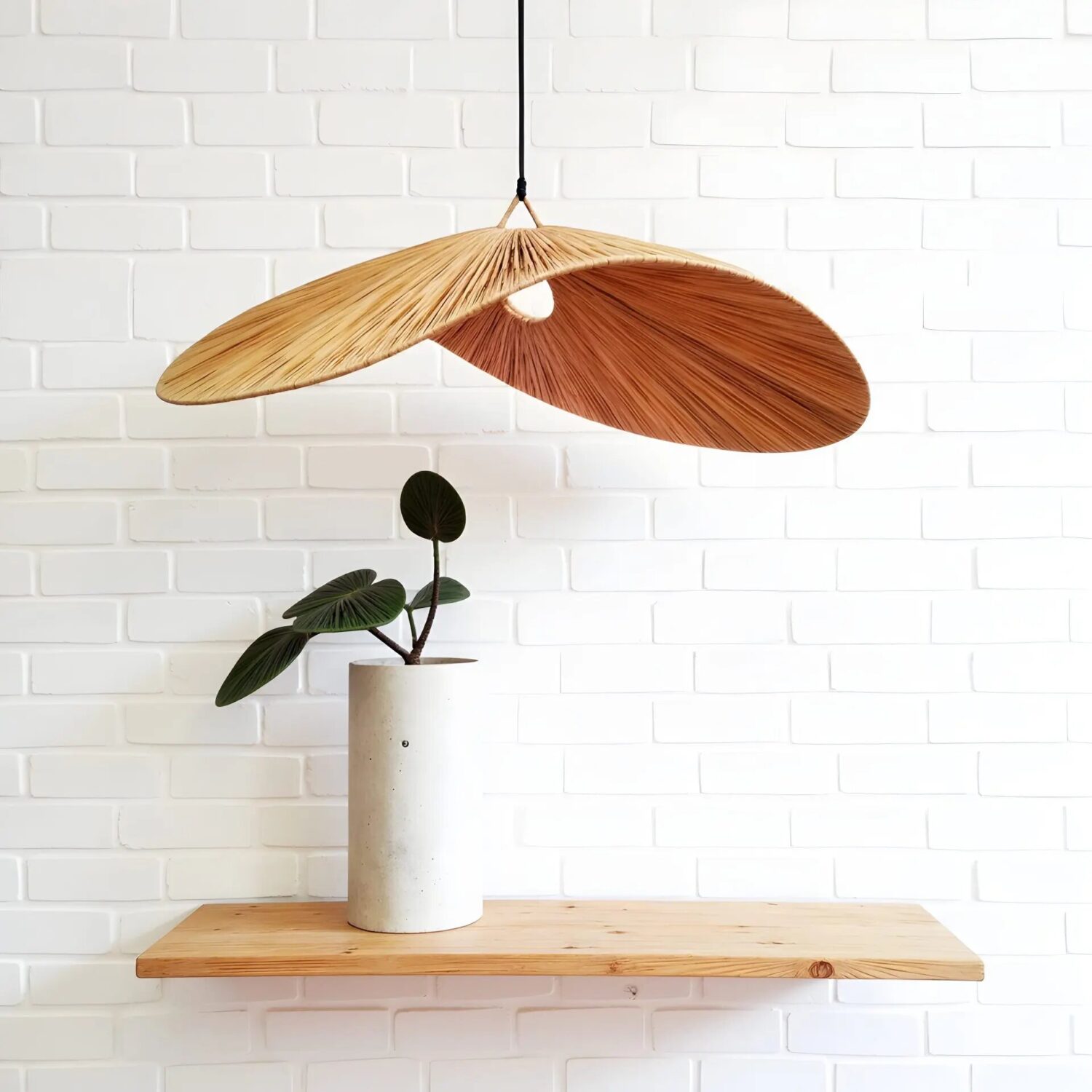 Handwoven wood pendant light with butterfly wings design in natural two-tone veneer against white brick wall Handwoven wood pendant light with butterfly wings design in natural two-tone veneer against white brick wall