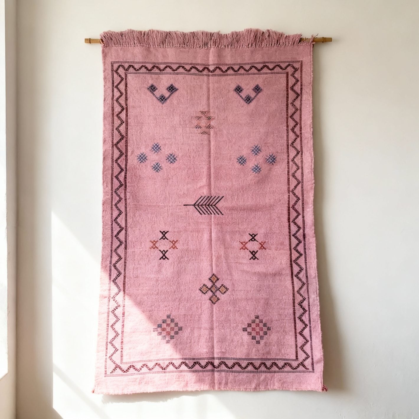 Pink cactus silk rug with geometric Berber motifs displayed on wood floor in living room setting Pink cactus silk rug with geometric Berber motifs displayed on wood floor in living room setting