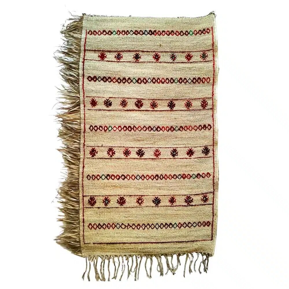 Handwoven straw runner rug with red Berber star embroidery and fringe on white background