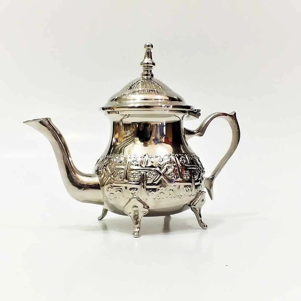 Footed embossed silver teapot with cabriole legs, domed finial lid, and scroll handle on white background Footed embossed silver teapot with cabriole legs, domed finial lid, and scroll handle on white background
