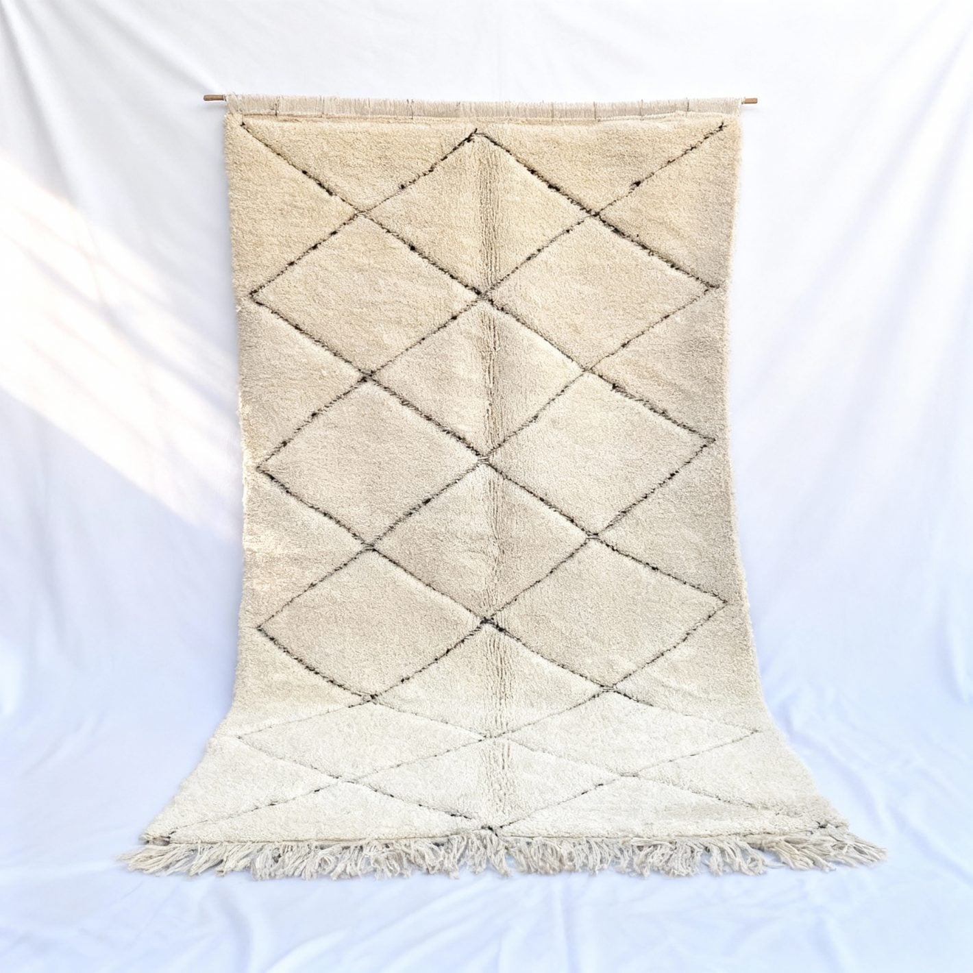 Ivory white Beni Ourain rug with handwoven Berber diamond pattern displayed on white backdrop Ivory white Beni Ourain rug with handwoven Berber diamond pattern displayed on white backdrop