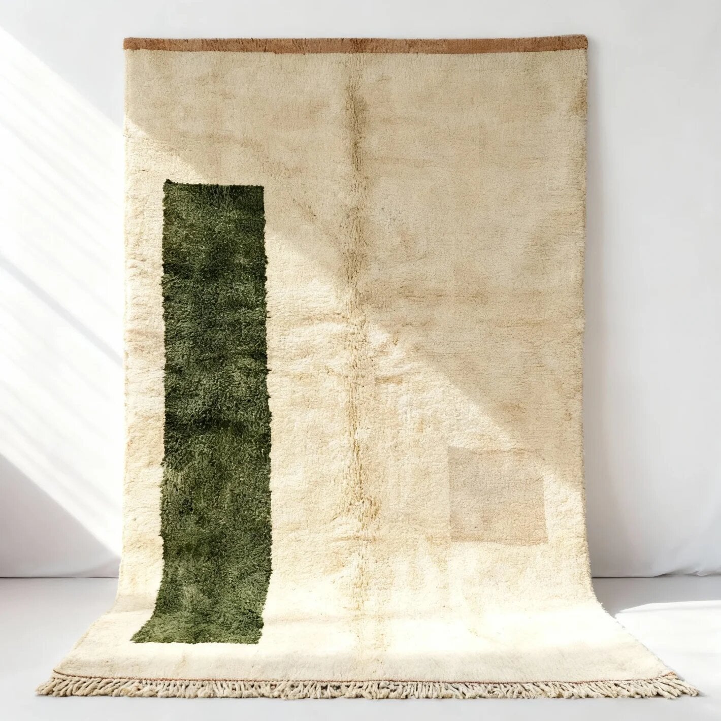 Cream green bohemian wool rug laid flat with bold olive-green vertical accent stripe, brown border, and knotted fringe