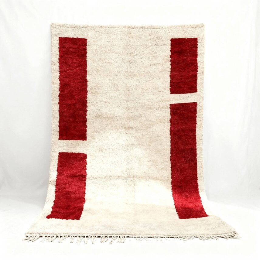 Handwoven Moroccan wool rug with bold red geometric blocks on cream background and natural fringe