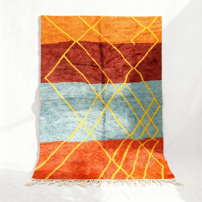 Yellow geometric Moroccan wool rug with Azilal diamond lattice on orange, burgundy, and turquoise stripes, hanging display
