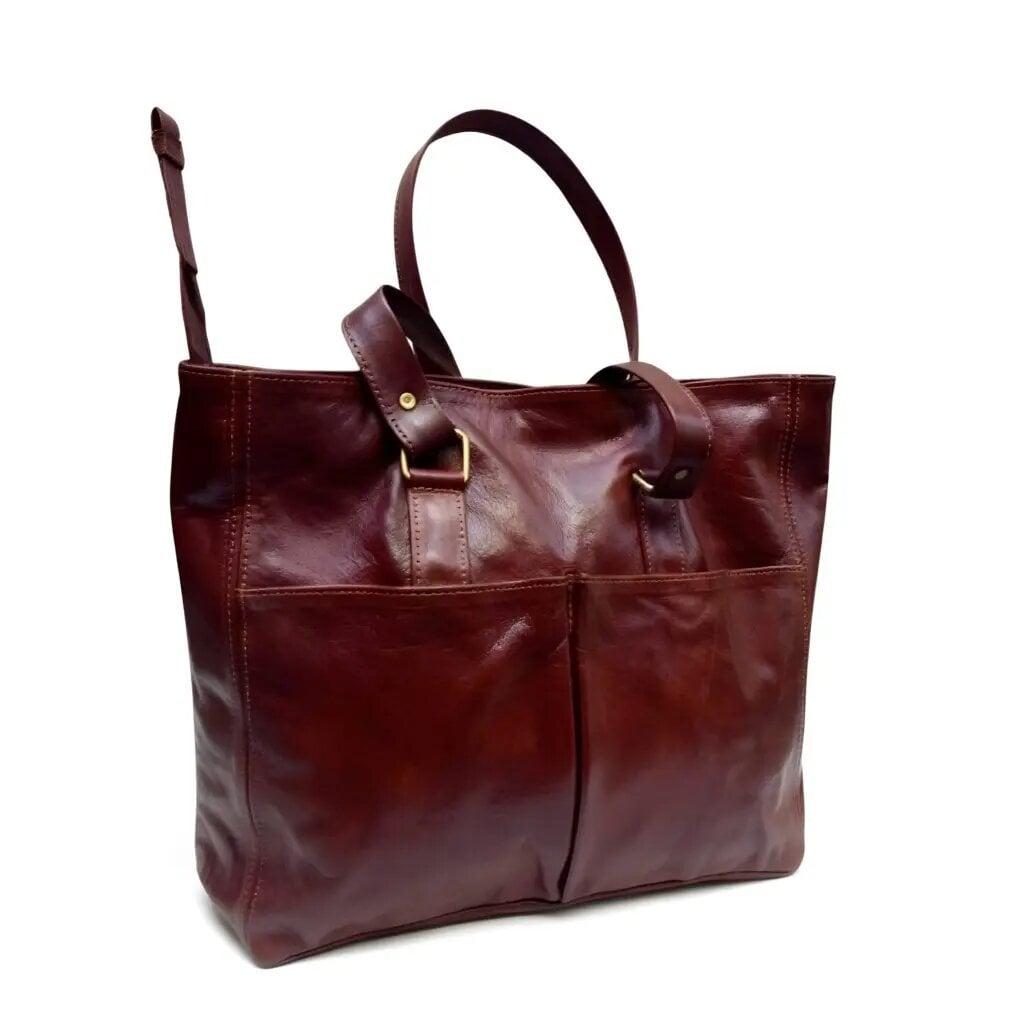 Burgundy brown leather tote bag with brass buckle pockets and contrast stitching on white studio background