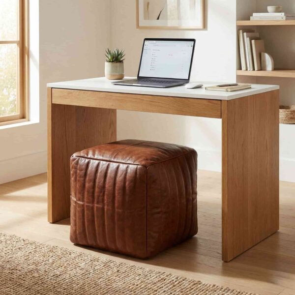 Channel stitched leather cube ottoman used as desk seating in a modern home office with natural wood furniture Channel stitched leather cube ottoman used as desk seating in a modern home office with natural wood furniture
