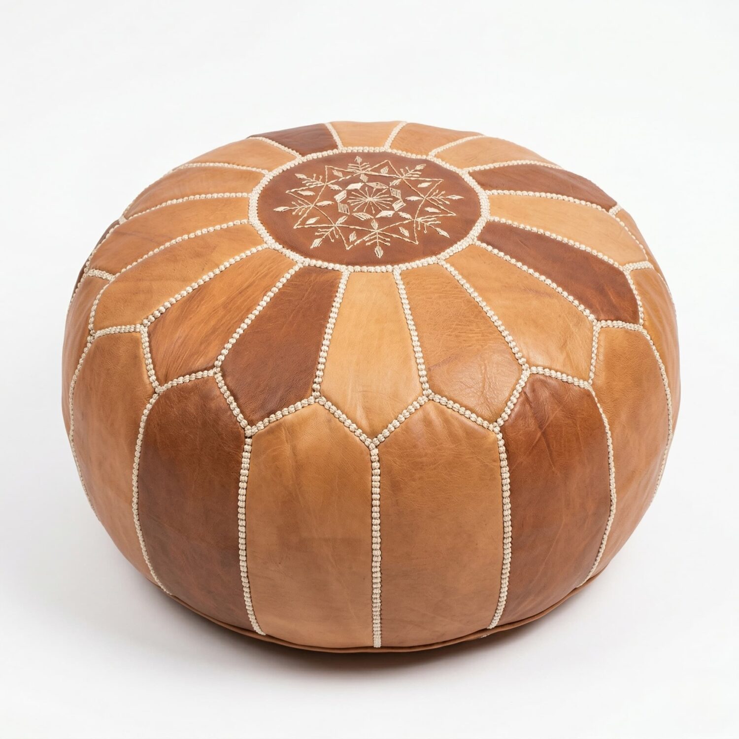 Natural leather round pouf featuring hand-embroidered geometric star design and whipstitched two-tone tan and brown panels.