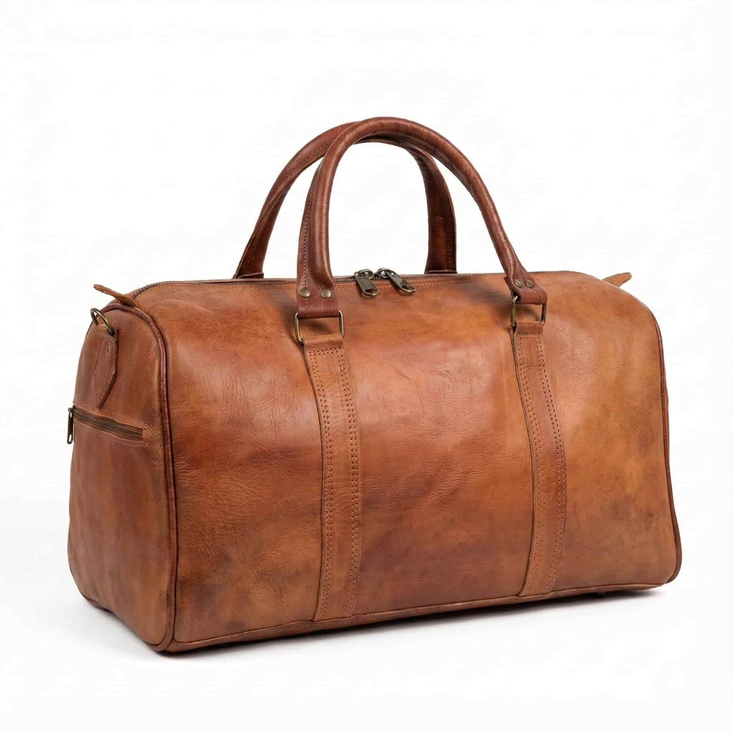 Handcrafted cognac leather travel bag on white background showing full-grain leather, dual zipper closure, and solid brass hardware