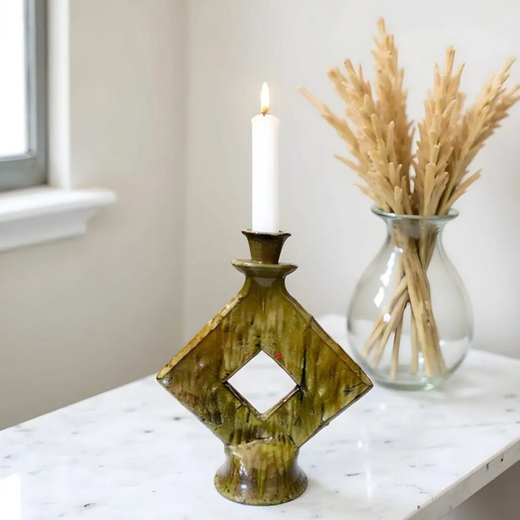 Tamegroute green ceramic candle holder with diamond cutout on white marble table beside dried wheat vase Tamegroute green ceramic candle holder with diamond cutout on white marble table beside dried wheat vase