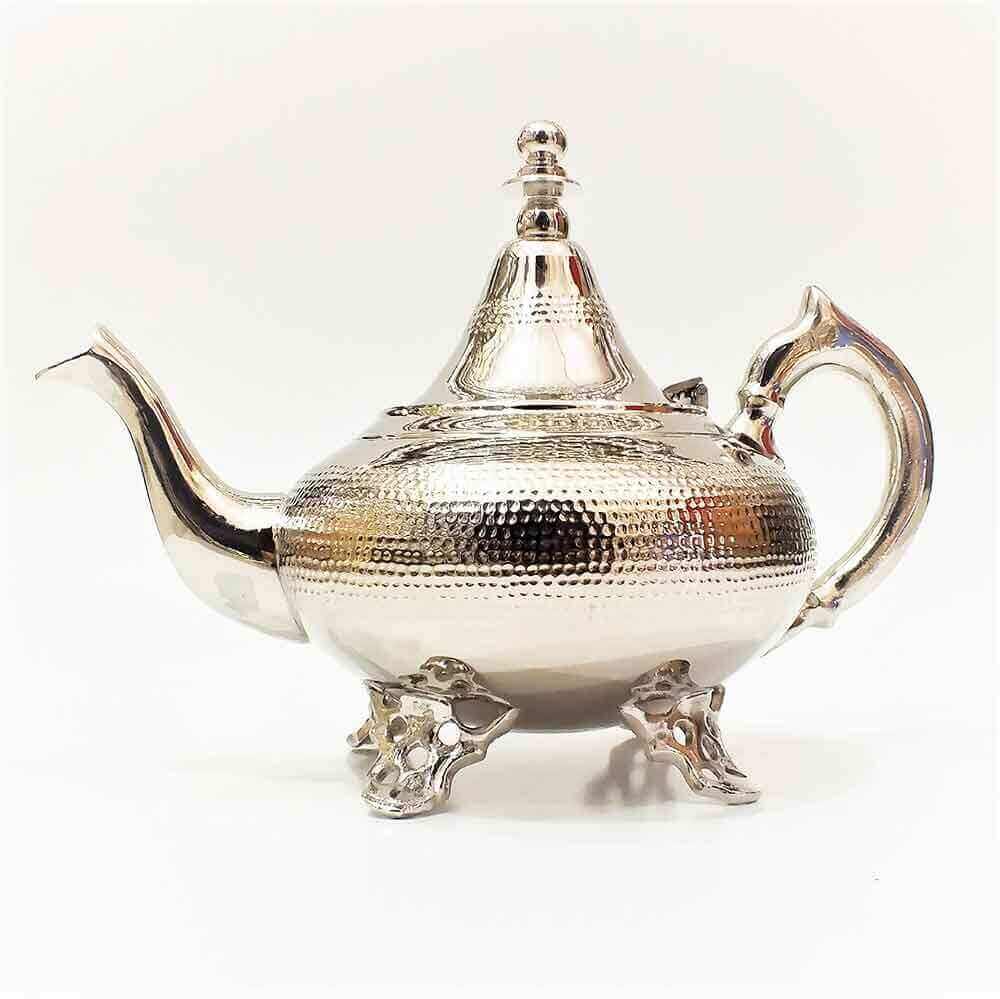 Dual finish hammered silver teapot with bulbous body, conical lid, and baroque scrollwork feet on white background Dual finish hammered silver teapot with bulbous body, conical lid, and baroque scrollwork feet on white background