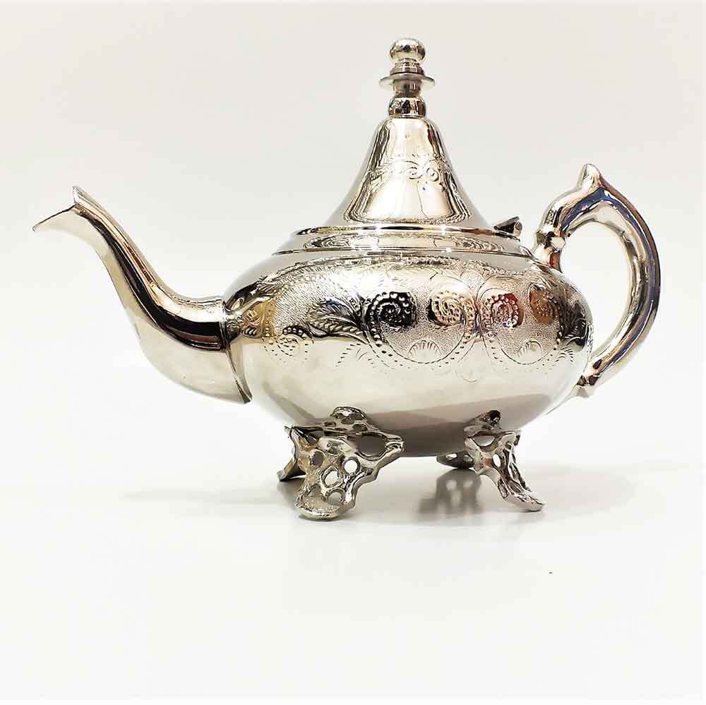 Oblate engraved silver teapot with circular medallion motifs and pierced openwork feet on white background
