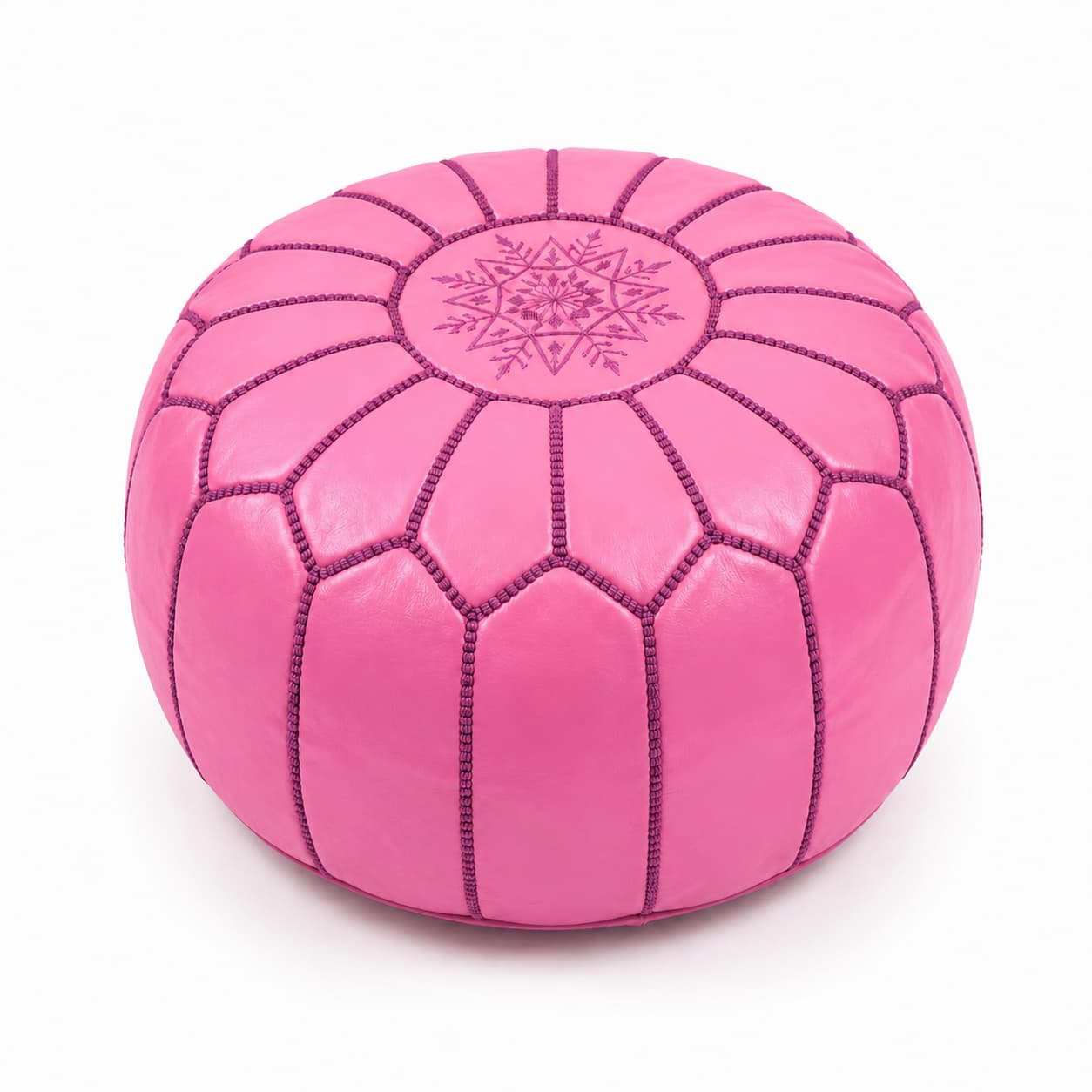 Vibrant pink leather round ottoman featuring traditional handcrafted patchwork goatskin and intricate embroidery on a wh Vibrant pink leather round ottoman featuring traditional handcrafted patchwork goatskin and intricate embroidery on a white background.