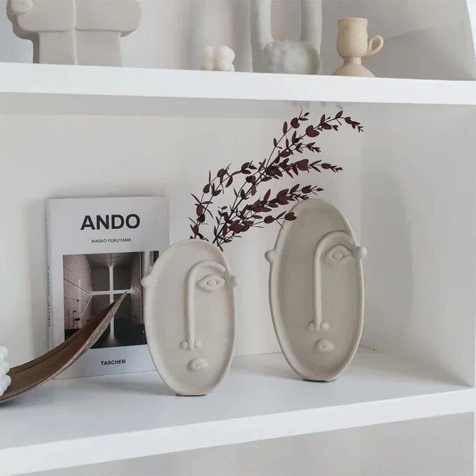White ceramic face vase set of 2 with abstract features on modern shelf with ANDO book and dried branches