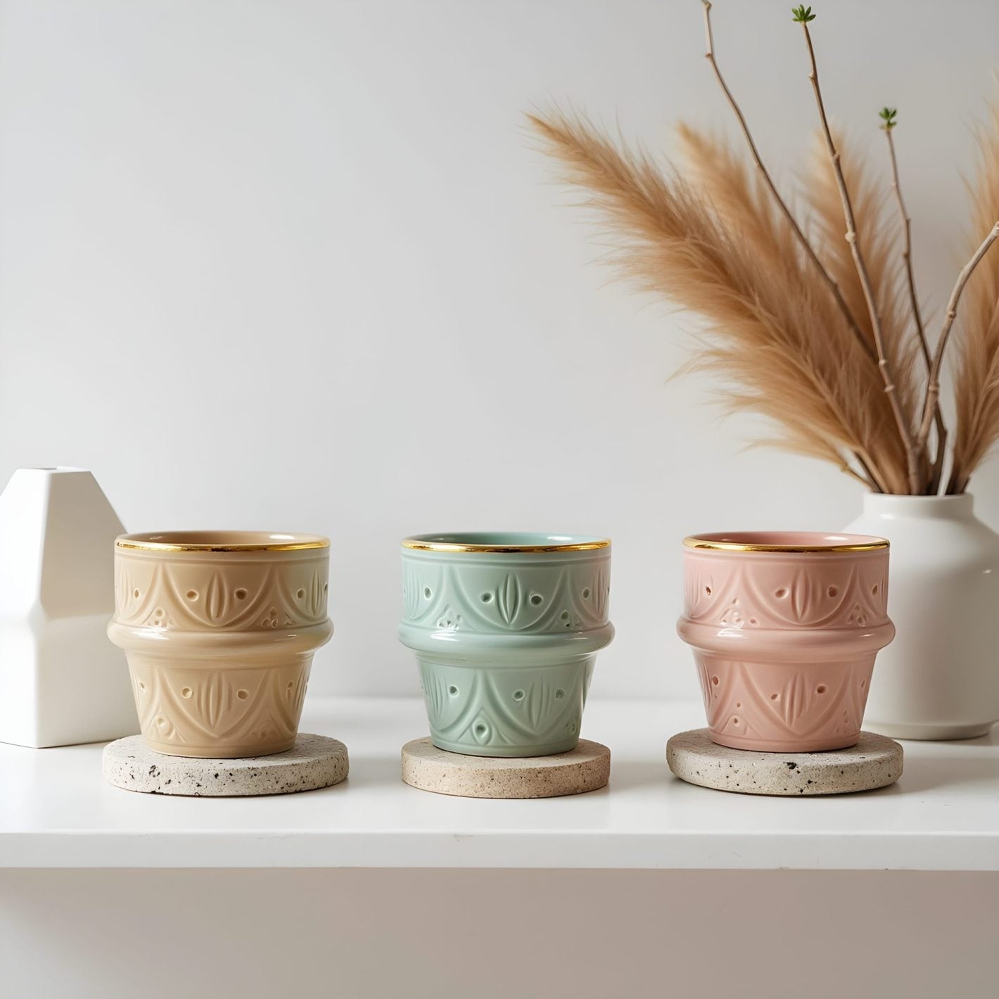Hand-decorated ceramic espresso cups in beige, mint, and pink with gold rims on stone coasters