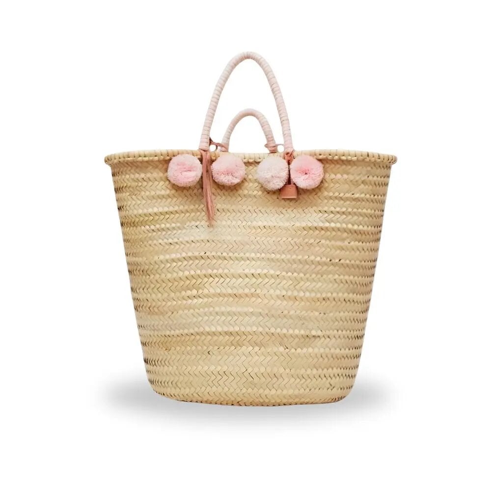 Handwoven pom pom straw tote bag with pink pompoms and wrapped cotton handles on white background