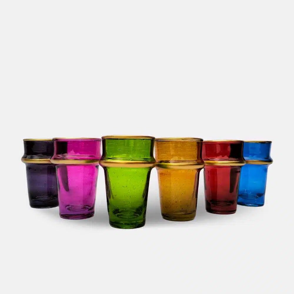 Six multicolor beldi tea glasses with gold enamel bands arranged in a row on a white background Six multicolor beldi tea glasses with gold enamel bands arranged in a row on a white background