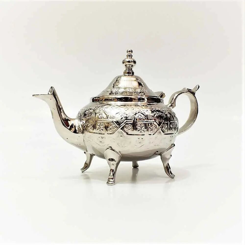 Large hand-carved silver teapot with geometric engraving, curved spout, domed lid, and four feet on plain white background