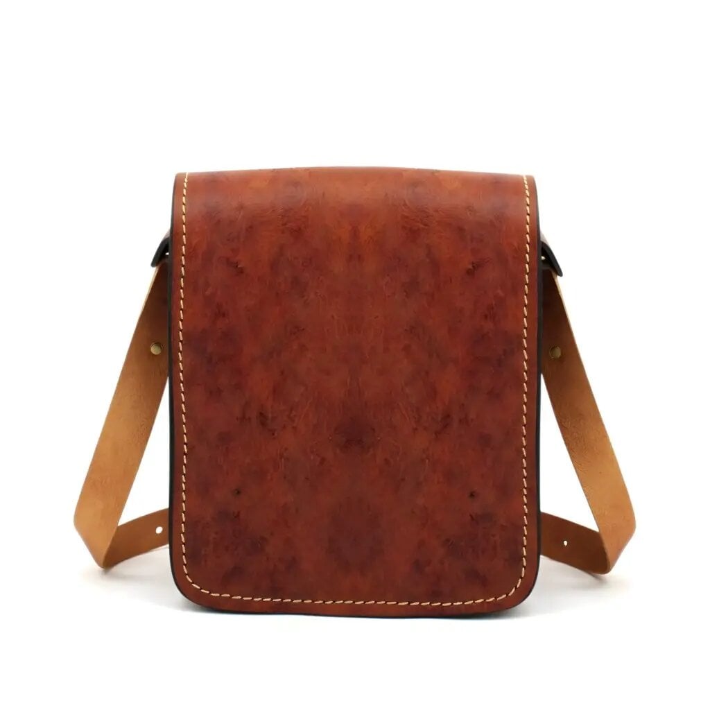 Cognac leather crossbody purse with flap closure, saddle stitching and adjustable strap, front view on white background