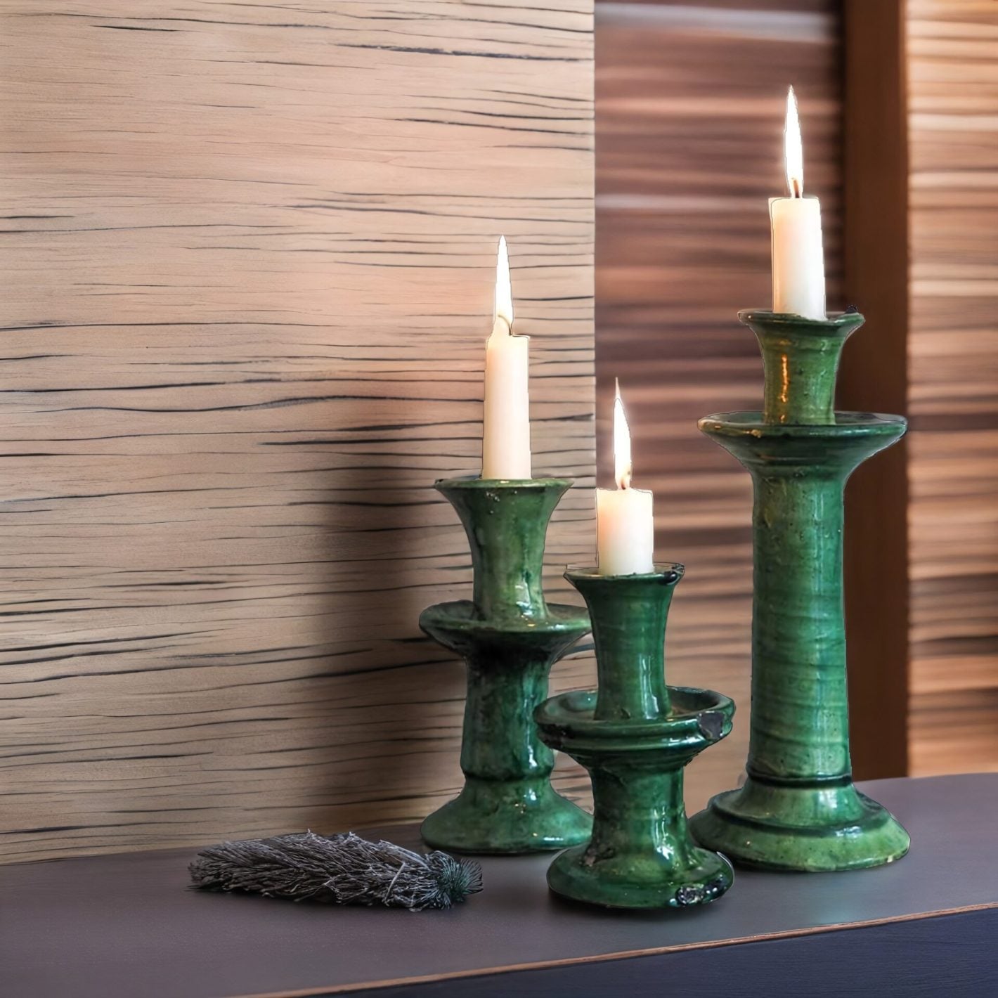 Set of green ceramic clay candle holders with crackle glaze and lit white candles on dark surface Set of green ceramic clay candle holders with crackle glaze and lit white candles on dark surface