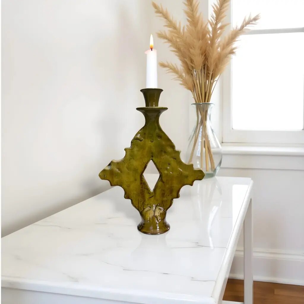 Handmade Tamegroute ceramic candle holder with diamond cutout in olive-green glaze on white marble surface Handmade Tamegroute ceramic candle holder with diamond cutout in olive-green glaze on white marble surface