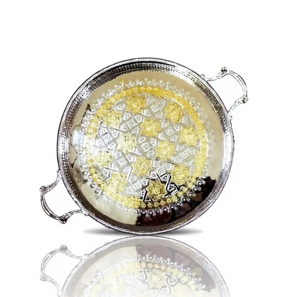 Overhead view of silver tray with gold accents featuring hand-engraved geometric arabesque pattern and ornate handles Overhead view of silver tray with gold accents featuring hand-engraved geometric arabesque pattern and ornate handles