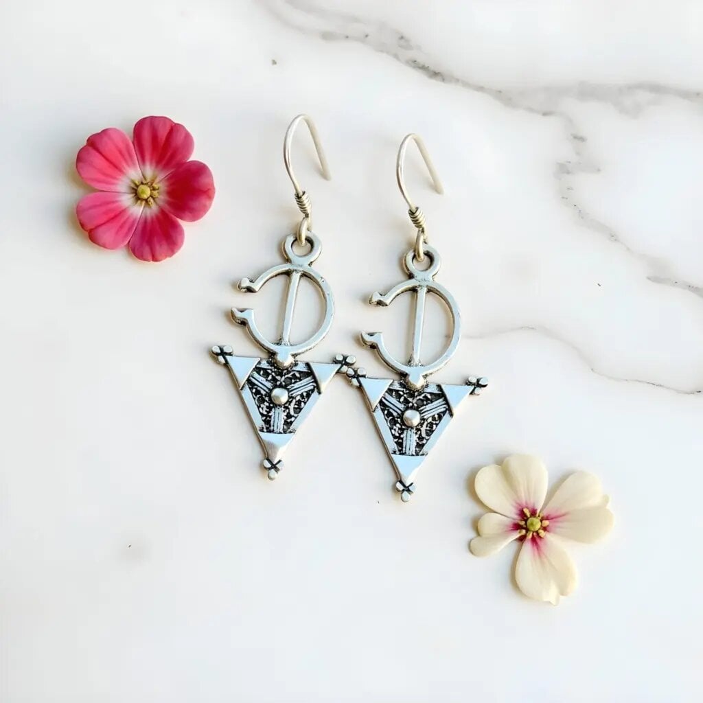 Sterling silver Berber earrings with triangle fibula design and intricate engravings on marble background