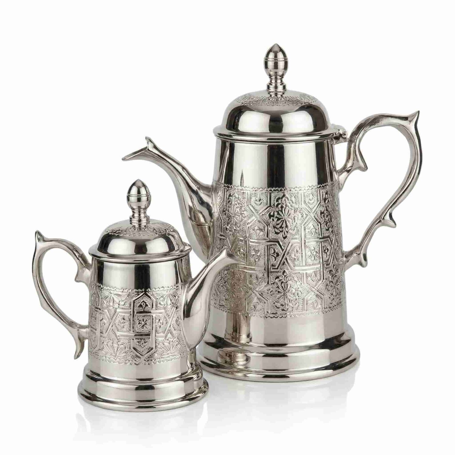 Two moroccan silver coffee server pot sizes with hand-engraved geometric medallions on white background Two moroccan silver coffee server pot sizes with hand-engraved geometric medallions on white background