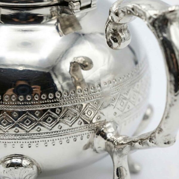 Close-up of hand-engraved interlocking diamond lattice pattern on silver teapot body