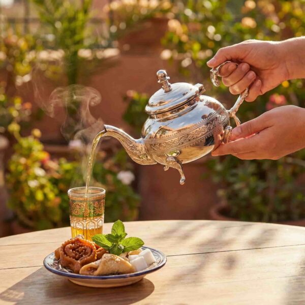 Diamond pattern silver teapot with tea glass, dates, and mint in a Moroccan tea service