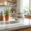 Diamond pattern silver teapot beside a potted plant on a white surface with geometric blocks