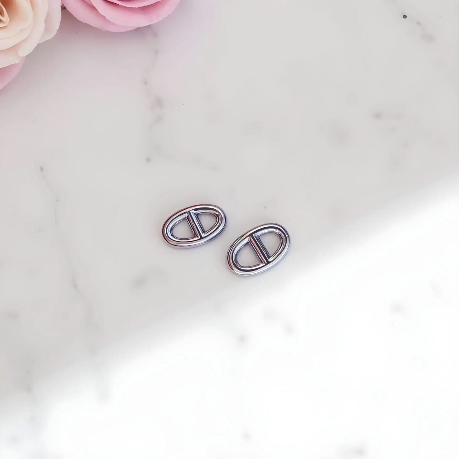 Sterling silver circle stud earrings with interlocking geometric design on white marble background
