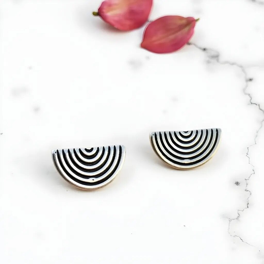 Sterling silver half circle earrings with black and white Berber stripe pattern on white marble background