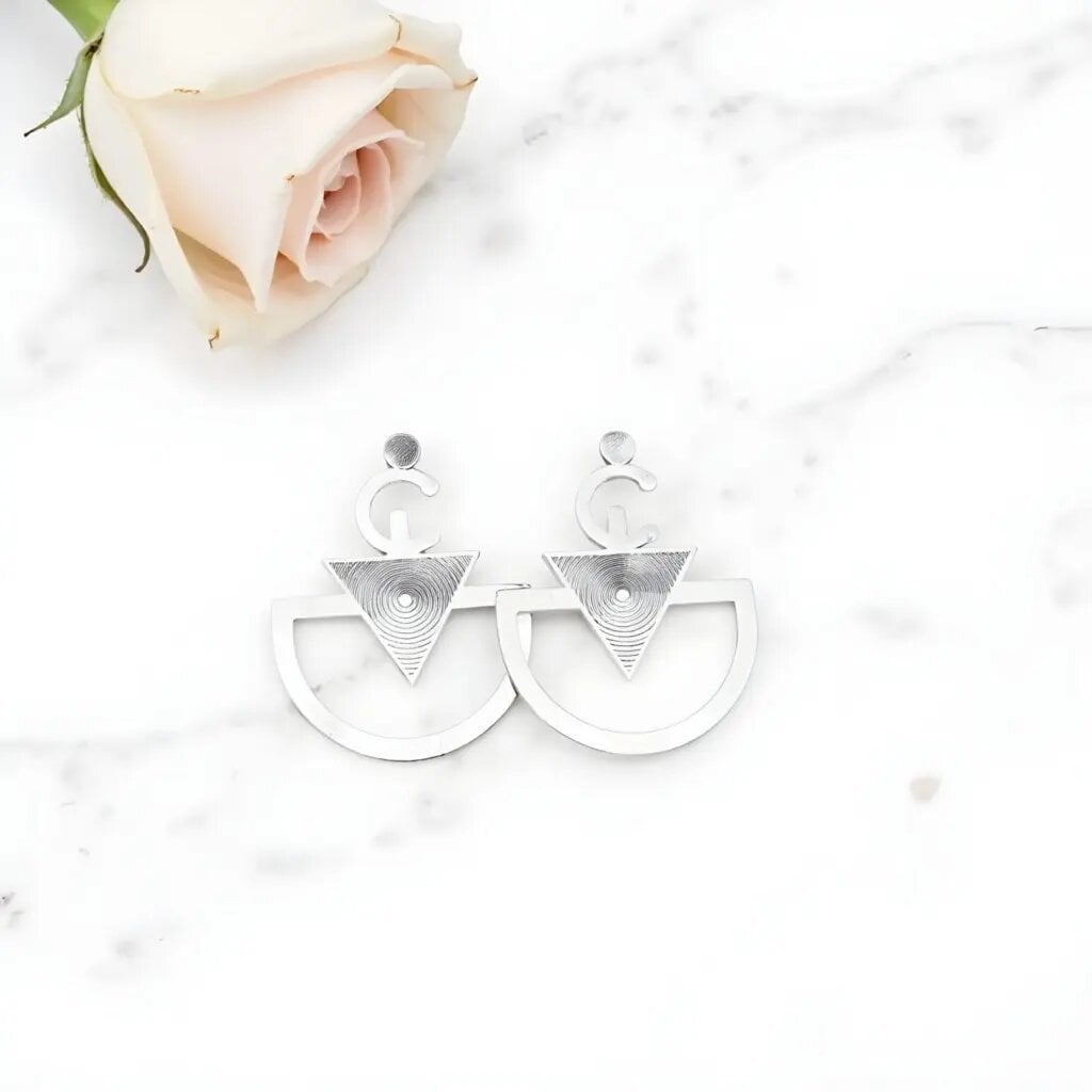 Geometric sterling silver earrings with spiral-etched triangle and curved hoop Berber design on marble Geometric sterling silver earrings with spiral-etched triangle and curved hoop Berber design on marble
