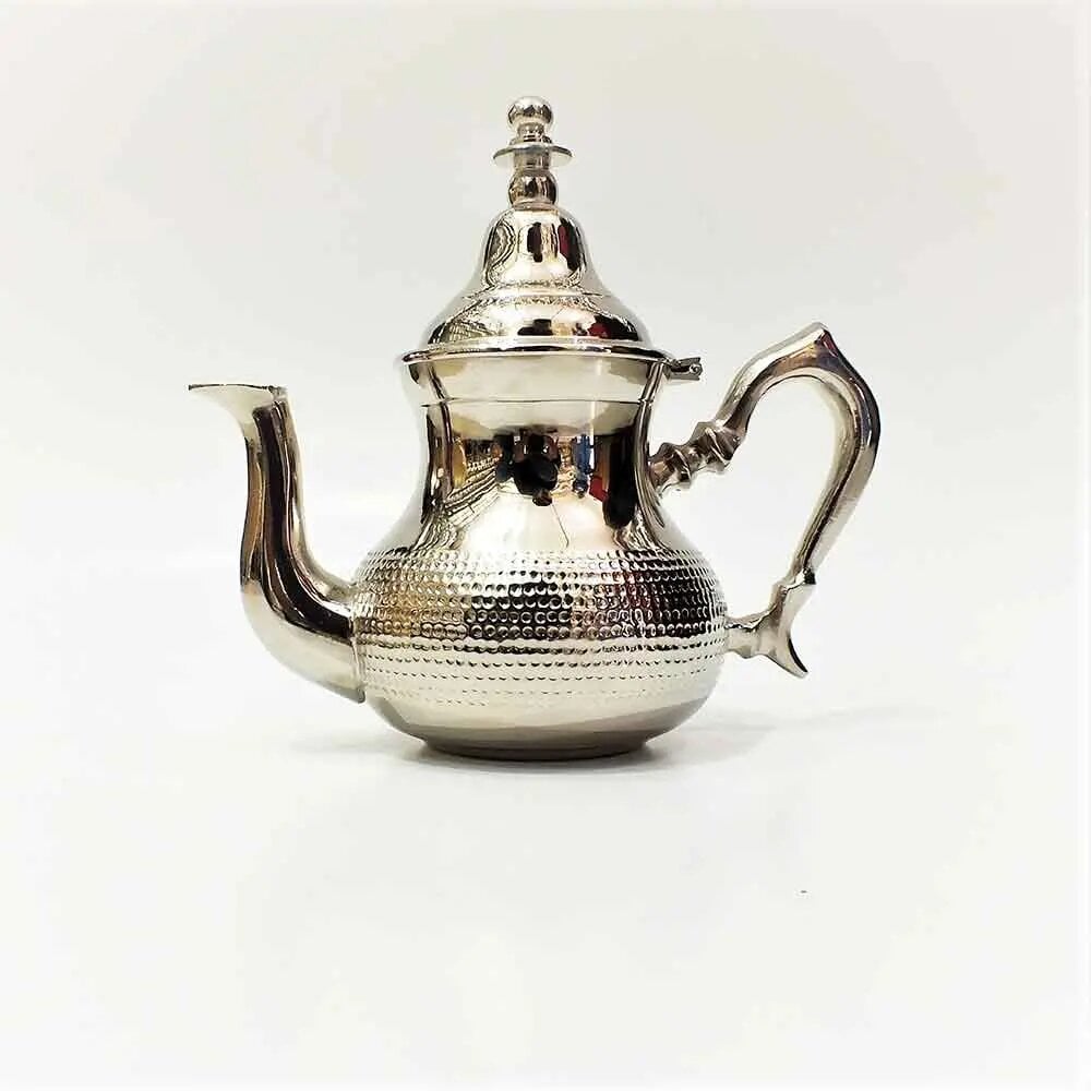 Minimalist hammered silver teapot with domed lid and finial on white studio background, showing flat base and textured midsection
