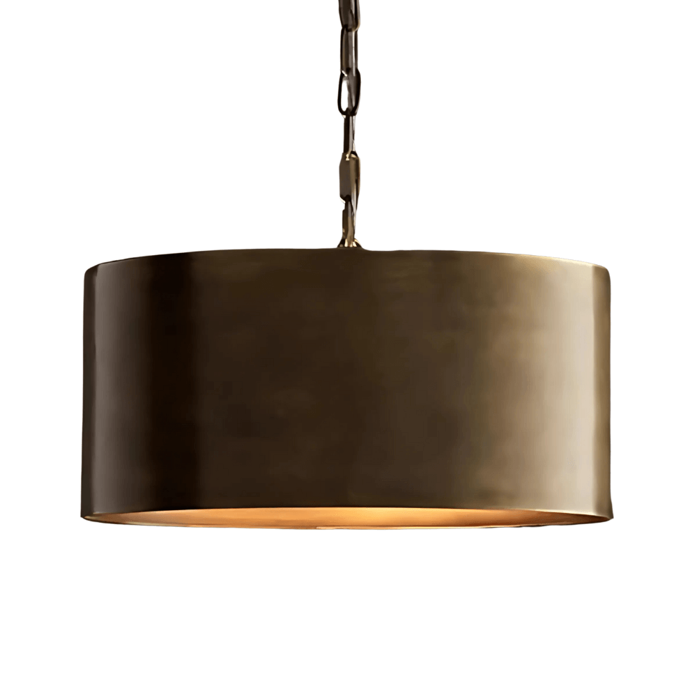 Modern brass drum pendant light with gradient finish and warm glow, suspended by chain against white background Modern brass drum pendant light with gradient finish and warm glow, suspended by chain against white background