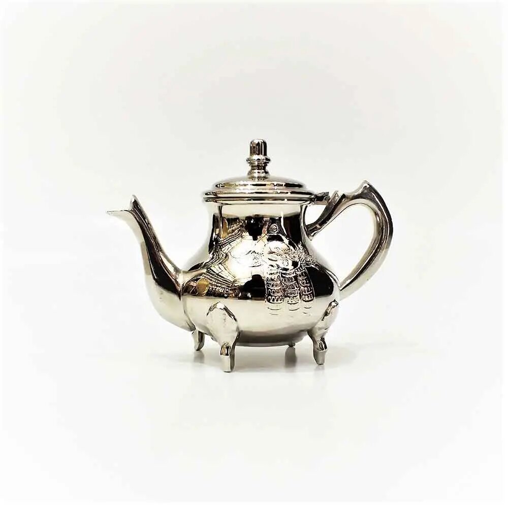 Silver-plated brass teapot with hamsa hand engraving, four ball feet, curved spout, and domed finial lid on white backgr Silver-plated brass teapot with hamsa hand engraving, four ball feet, curved spout, and domed finial lid on white background